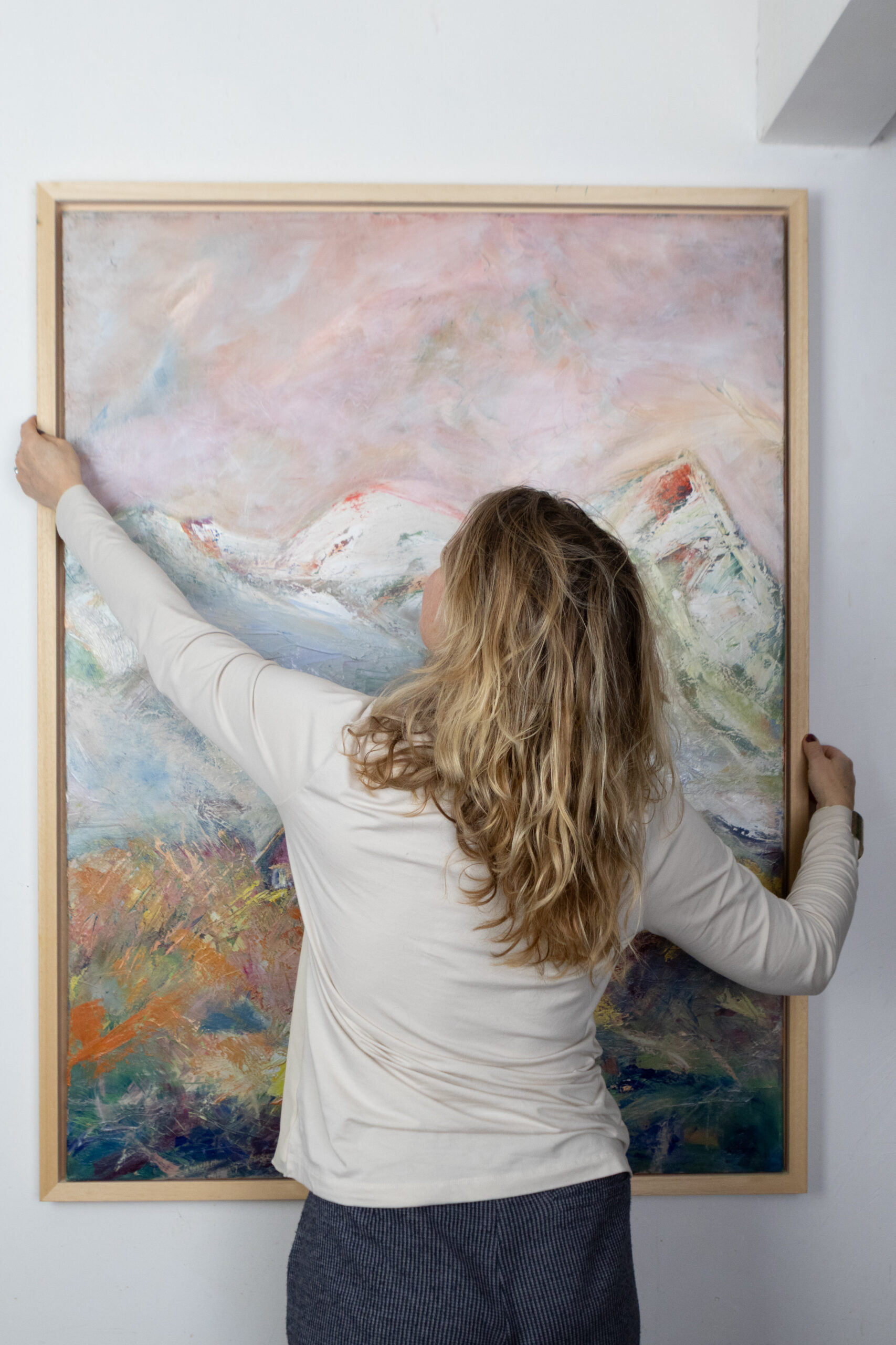 Leonoor Ruigrok placing an original painting on the wall while choosing art for the home-Artist in studio - visit contemporary - fine art studio Netherlands