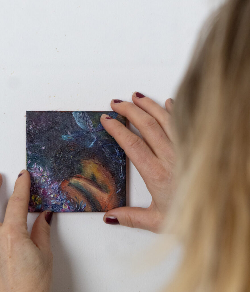 Leonoor Ruigrok placing a small original artwork on the wall, showing scale and detail when choosing art for a home