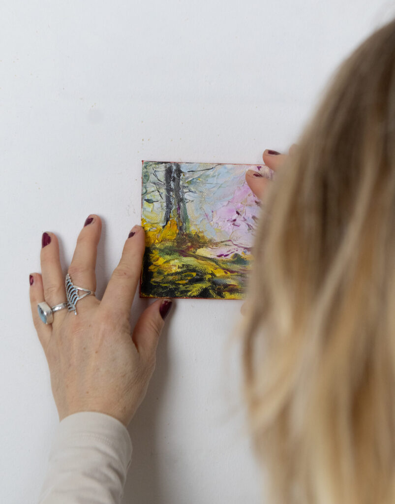 Leonoor Ruigrok placing a small original artwork on the wall, showing scale and presence when choosing art for the home