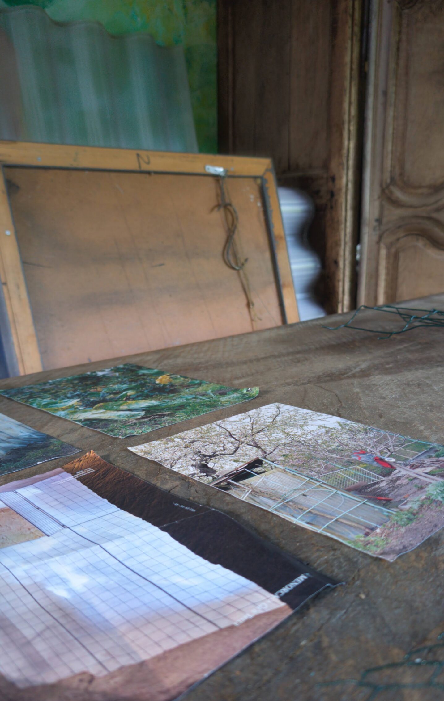 Rough wooden worktable in Leonoor Ruigrok’s hidden garden studio, with studies, materials and the back of a canvas.