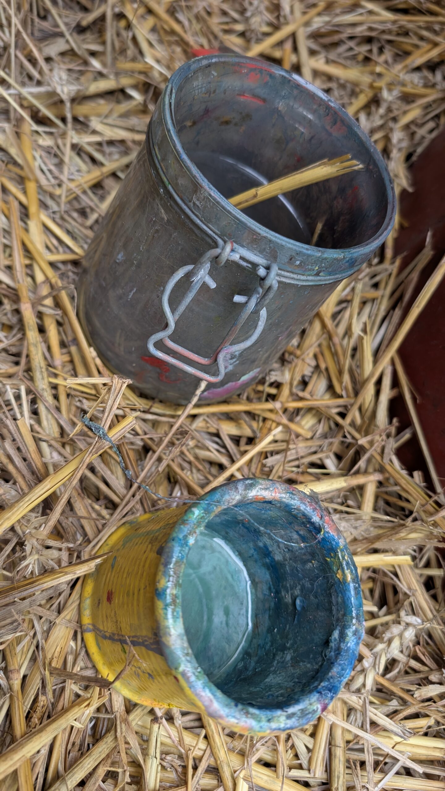 Painting materials in straw at Leonoor Ruigrok’s outdoor studio, showing material in the painting process with medium, brushes and studio gear.