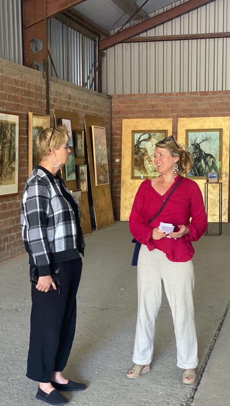 two people talking inside barn art exhibition paintings on wall Kunstschouw Zeeland Schuur De Wilde Leonoor Ruigrok