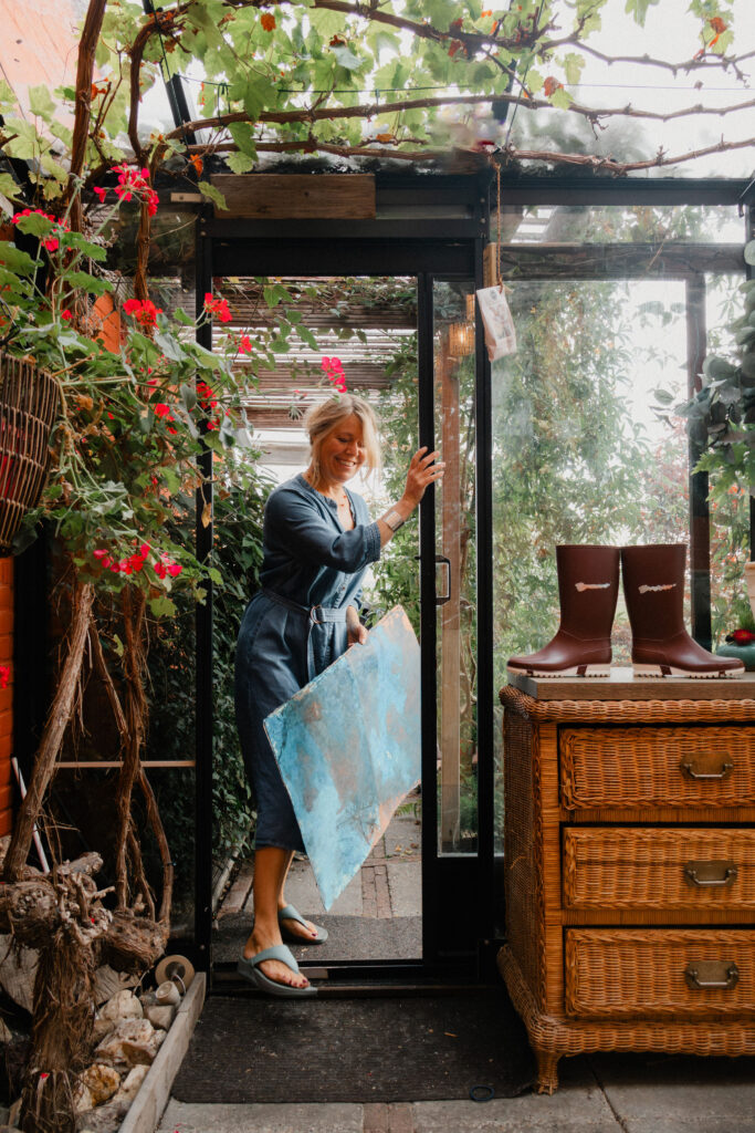 Leonoor Ruigrok standing in a glass doorway surrounded by plants
