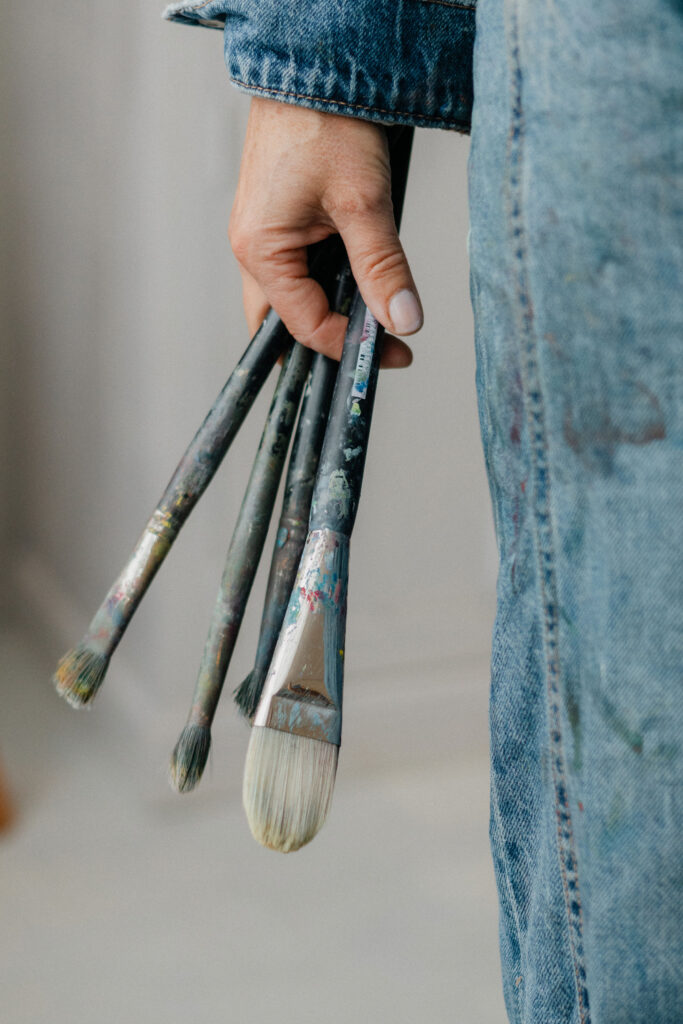 Artist Leonoor Ruigrok holding used paintbrushes in her hand