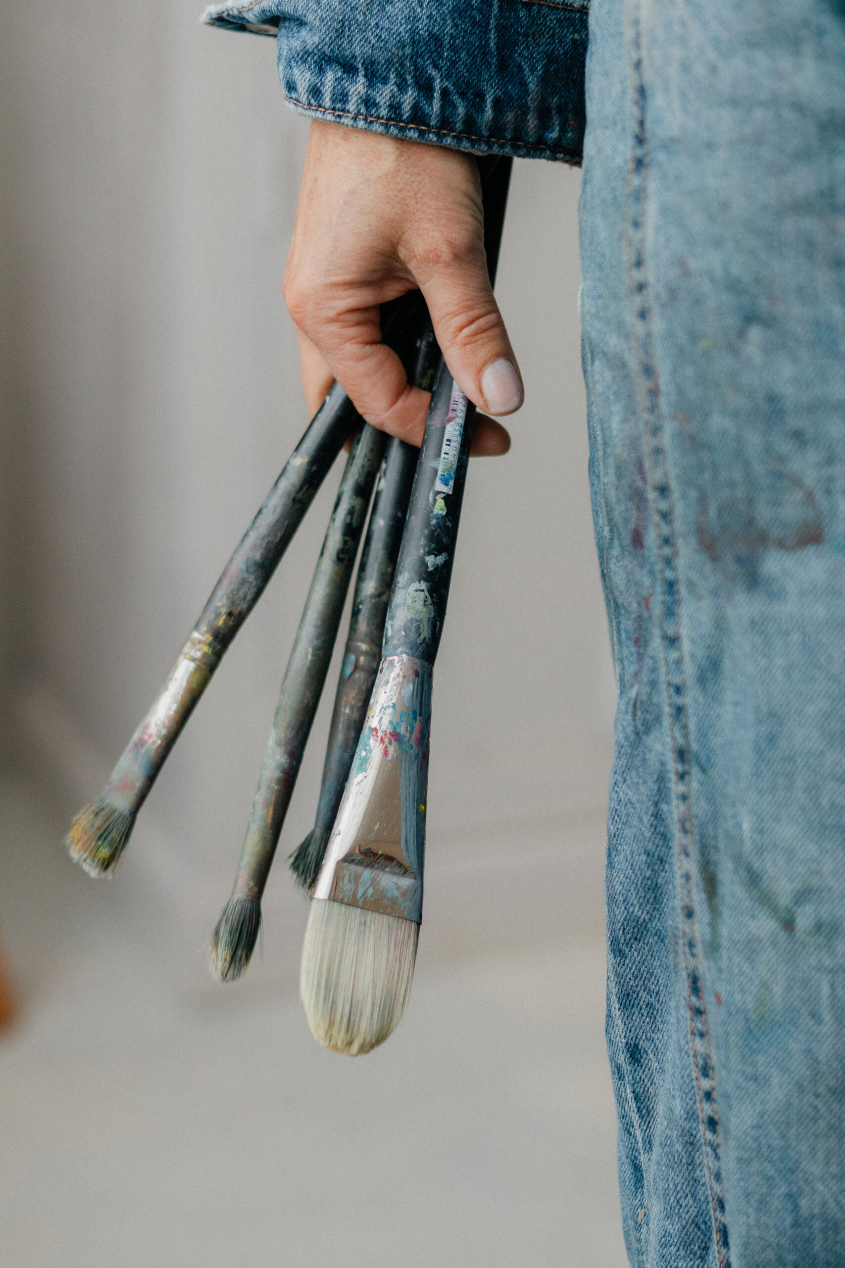 Artist Leonoor Ruigrok holding used paintbrushes in her hand